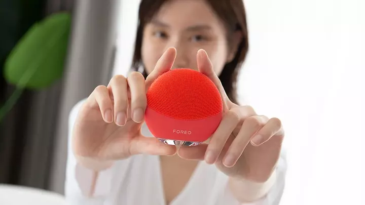 A young Asian woman showing of her LUNA facial cleansing brush